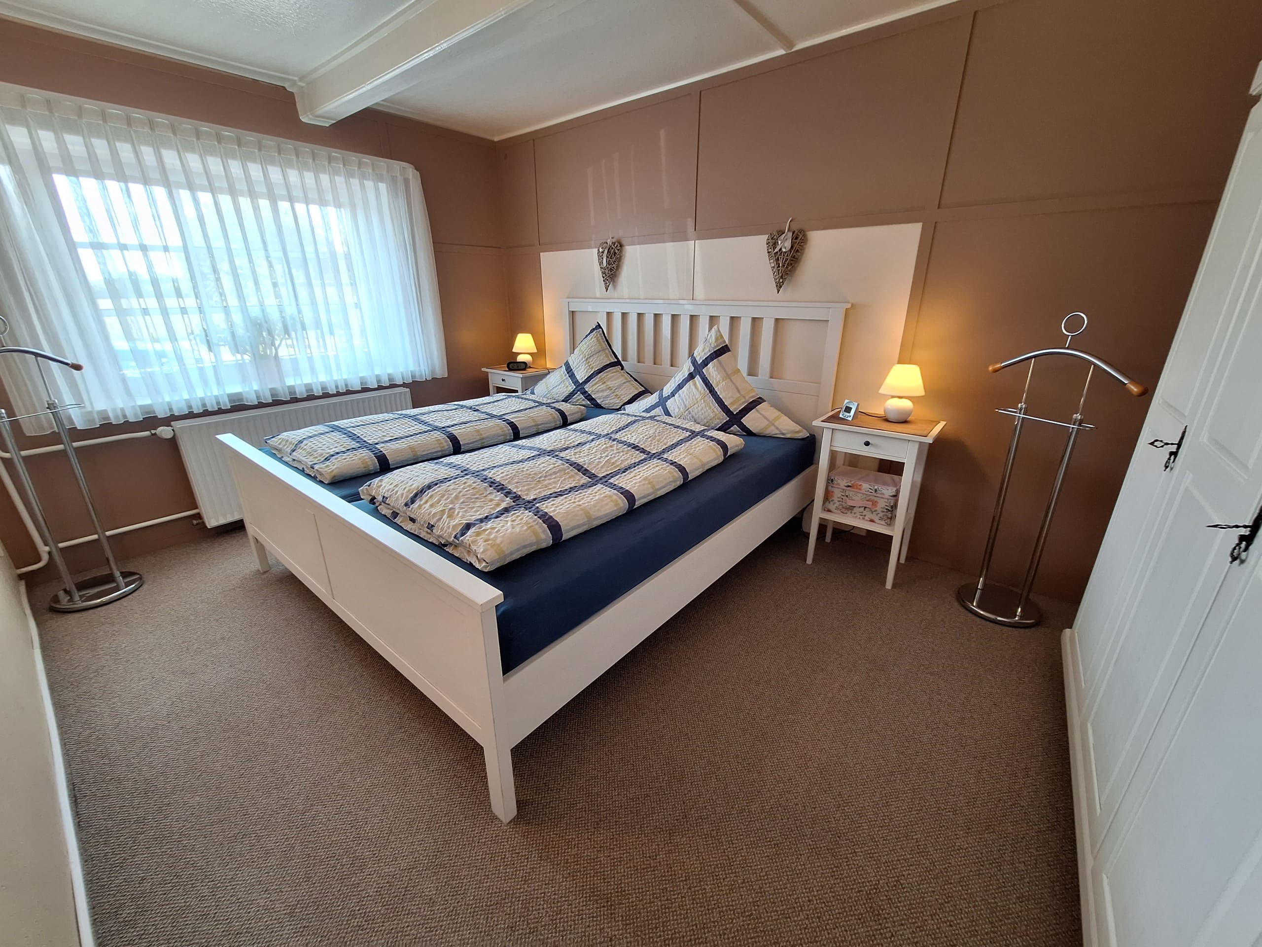 Gemütliches Schlafzimmer mit weißem Doppelbett aus Holz in der Ferienwohnung „Zur Linde“