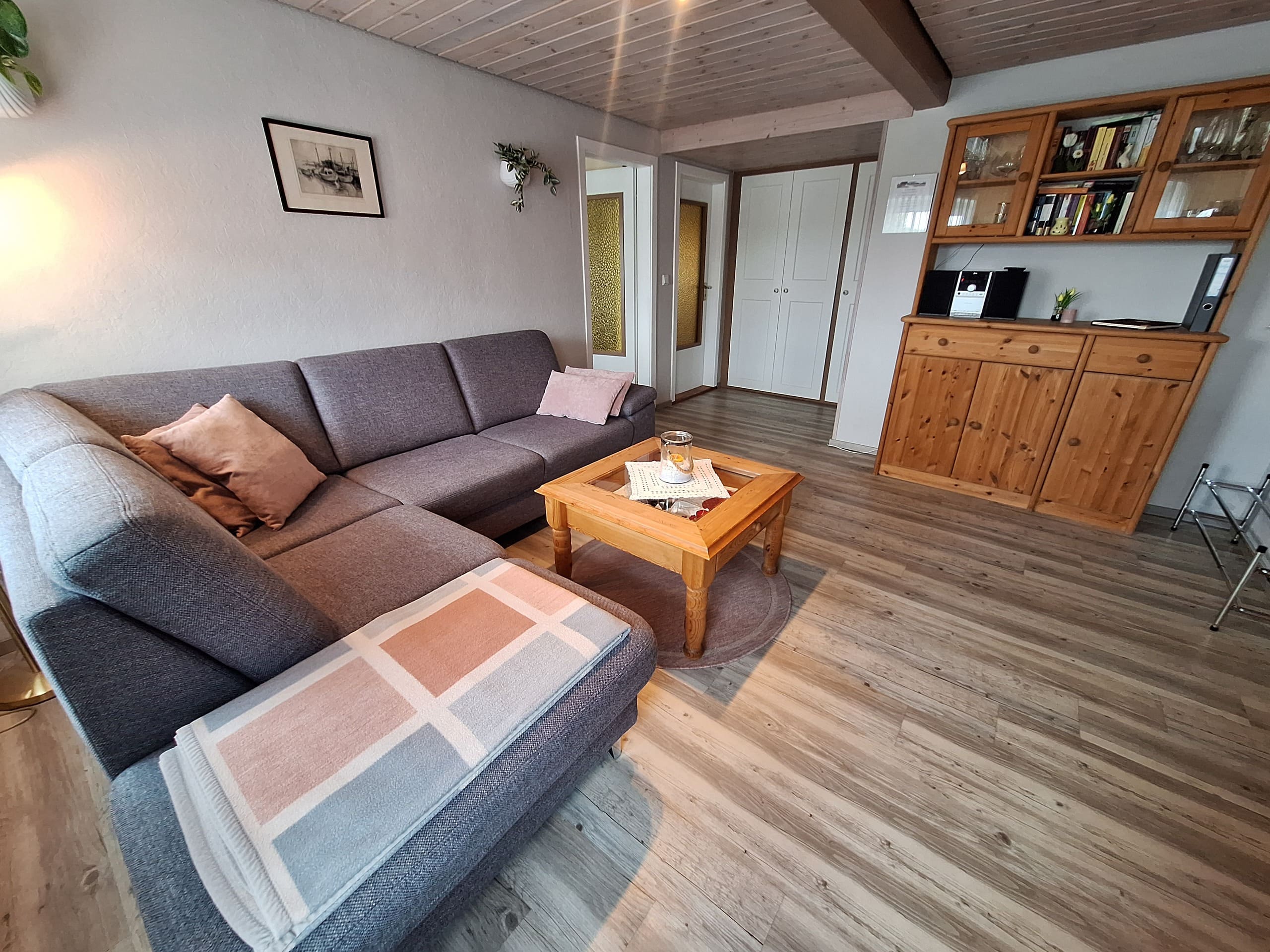 Gemütliches Wohnzimmer mit grauer Eckcouch der Ferienwohnung „Zur Linde“