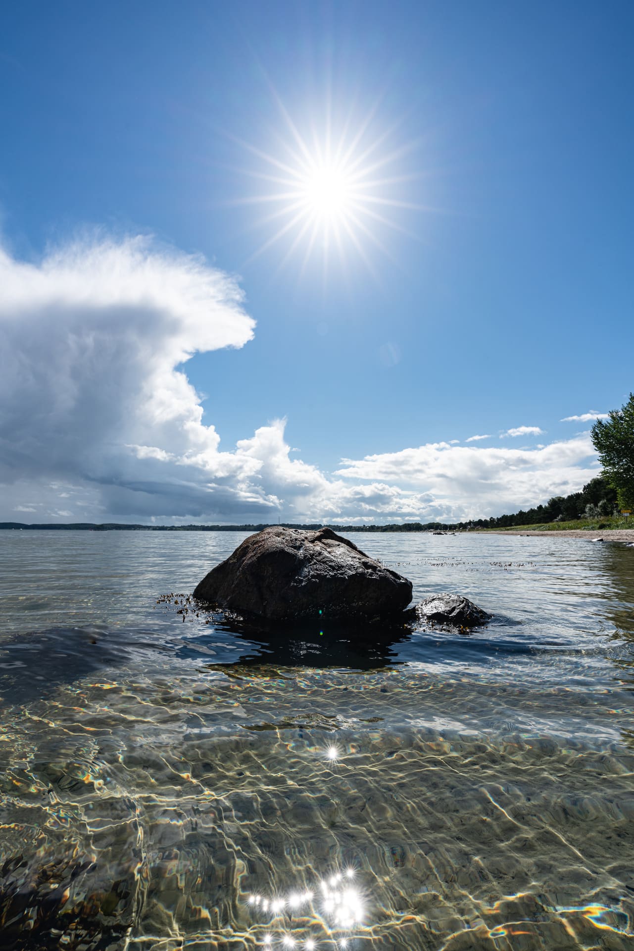 Stein im Wasser am Ufer der Ostsee, de Hälfte des Steins schaut aus dem Wasser