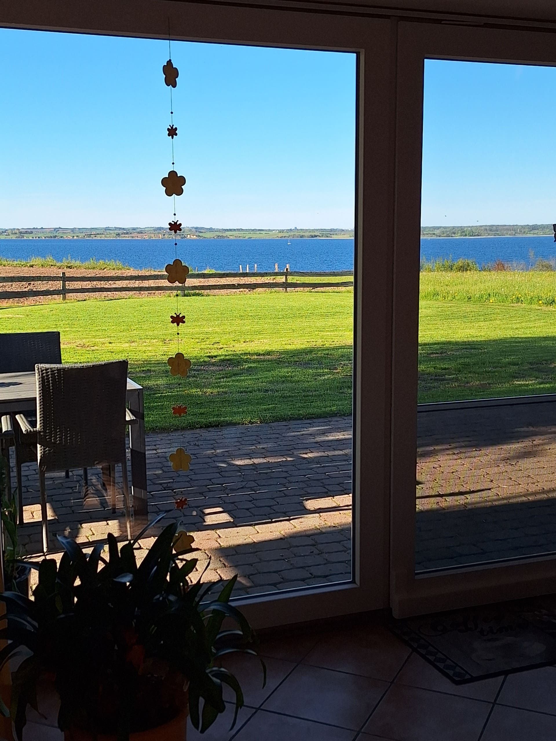 Blick aus dem Wohnzimmerfenster auf Garten, Ostsee und Dänemark